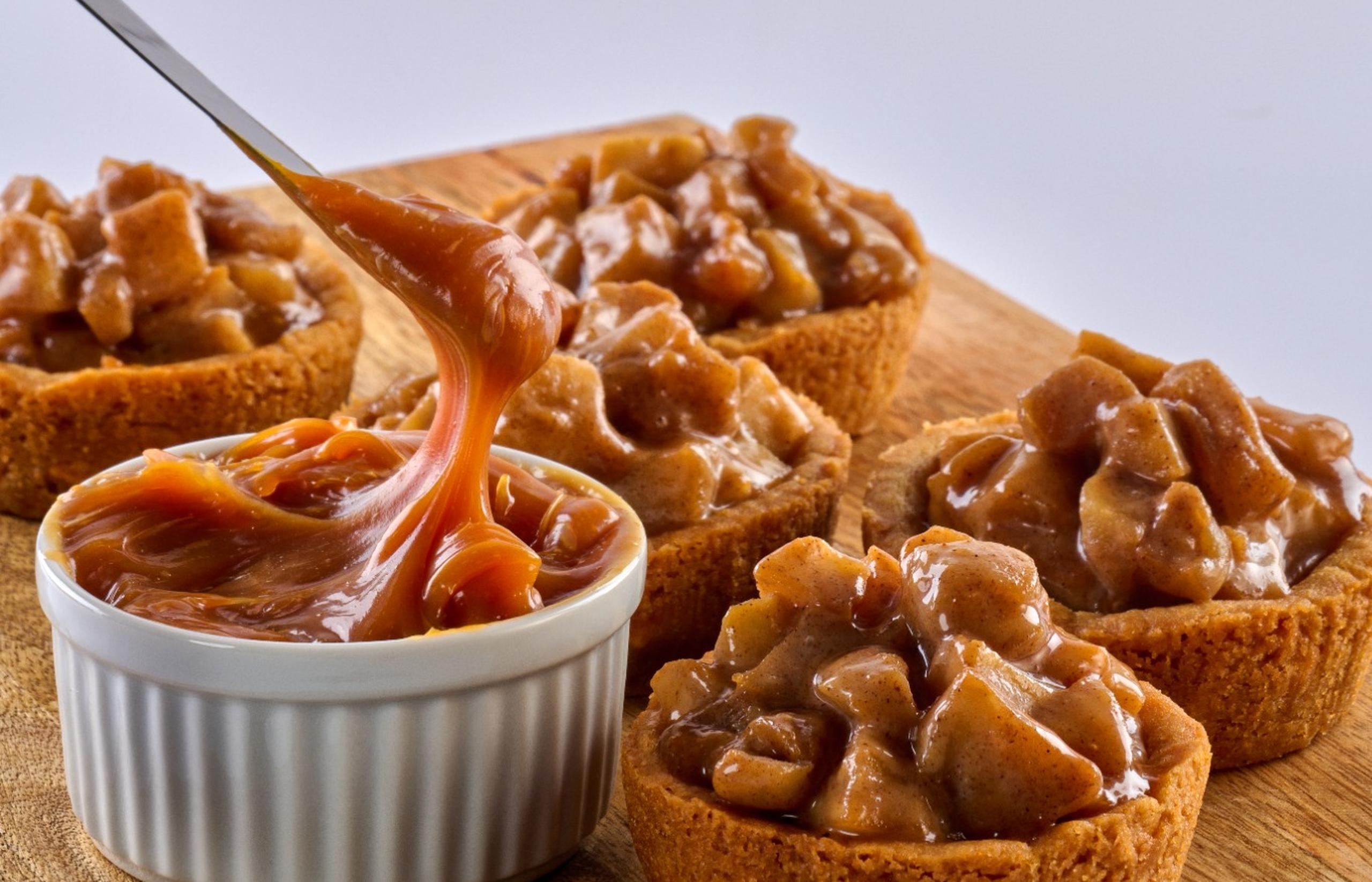 Golden caramel apple cookie cups filled with gooey caramel and spiced apple chunks, topped with a drizzle of caramel sauce.